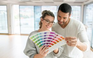 Happy couple painting their house and choosing a color from a palette